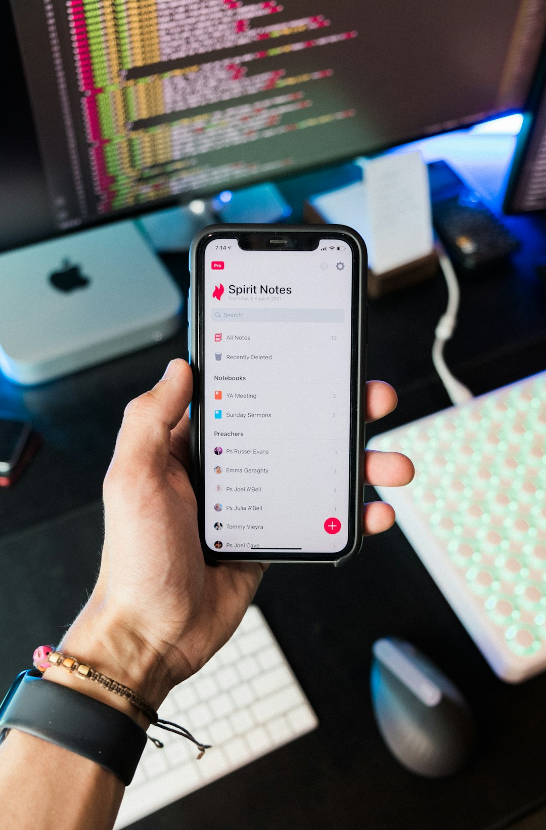 Man holding iPhone in front of desk.