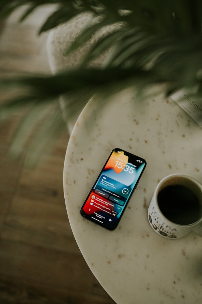 A smartphone displaying notifications next to a coffee cup on a marble table.